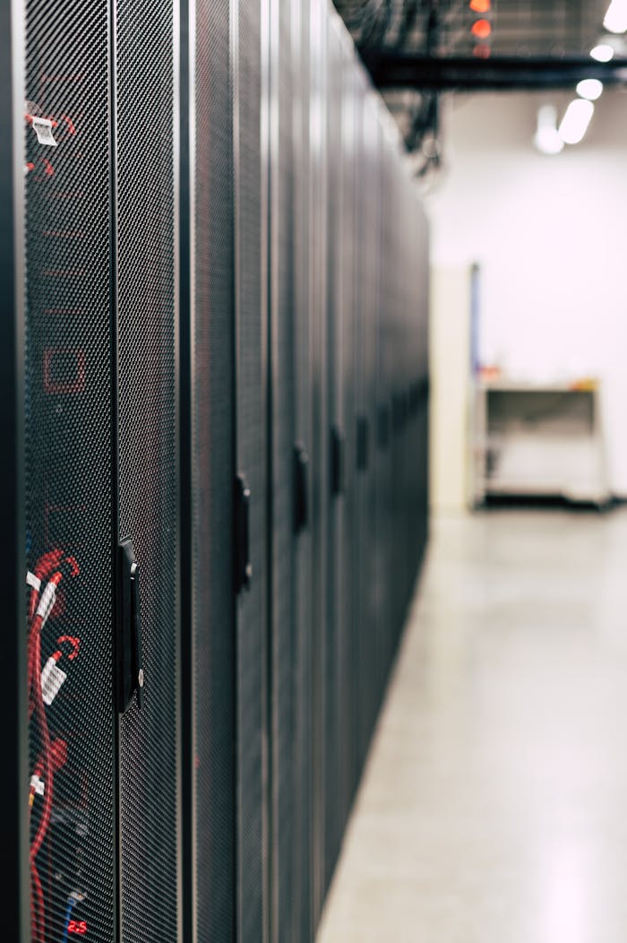 services-04 Metal black cabinets with servers inside with red wires connected standing in row in lighted room