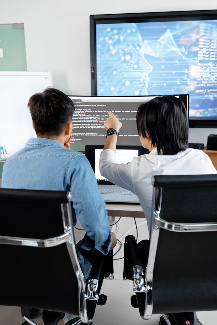 journey Two adults collaborating in an office, discussing code on a computer screen.